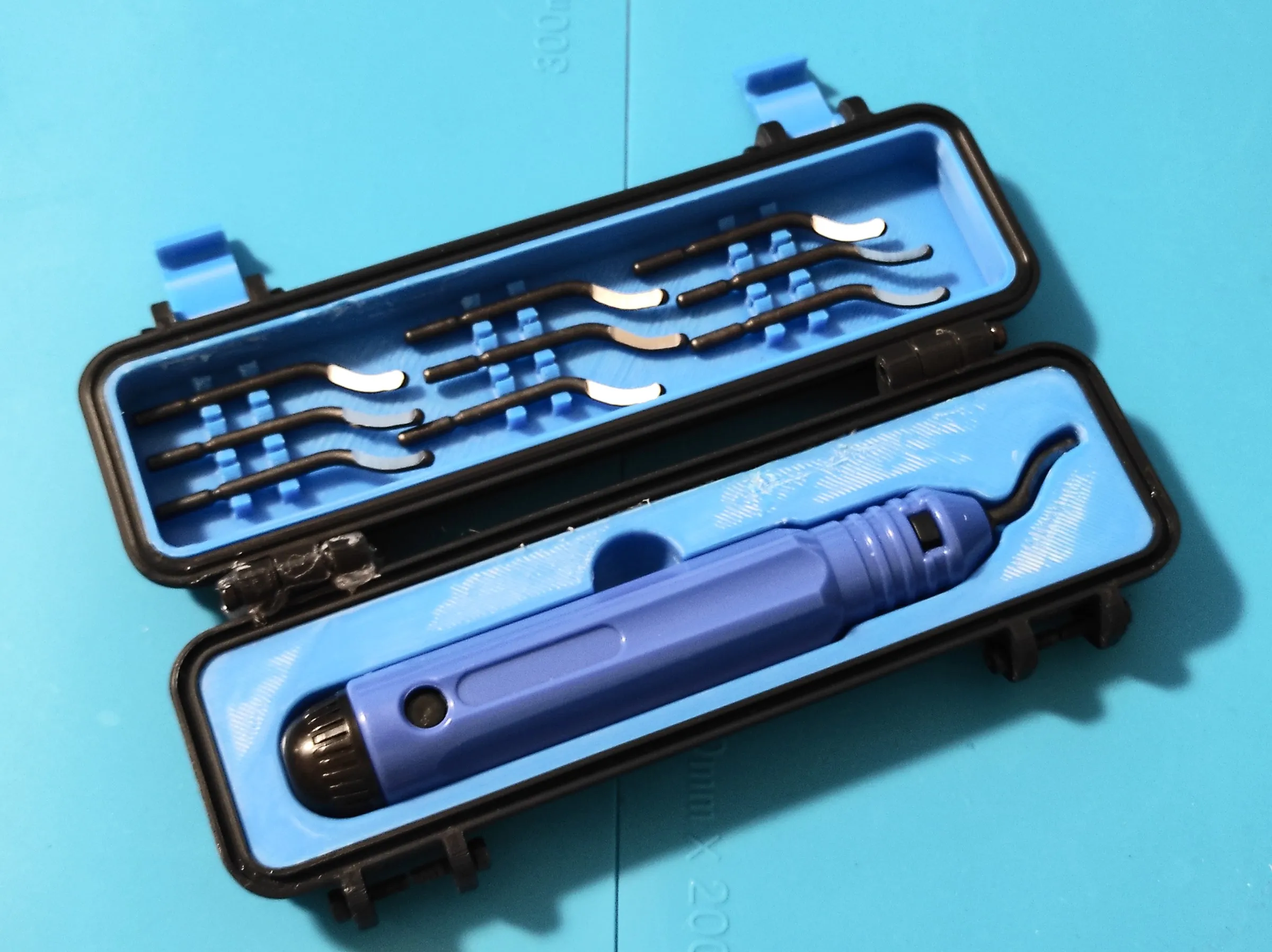 an open black and blue printed case holding a deburring tool and its spare blades